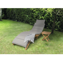 Scène de jardin avec une chaise longue en bois, un coussin et une table d''appoint