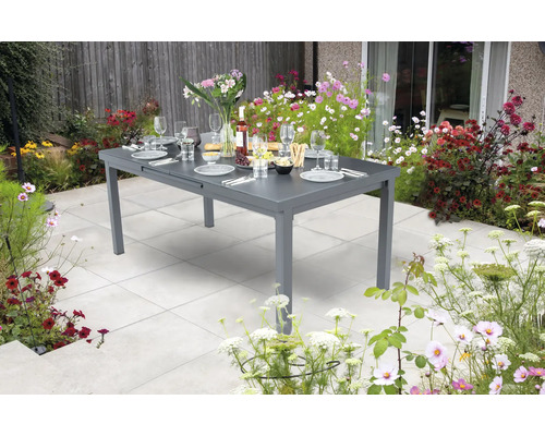 Table de jardin en métal dressée dans un jardin avec des fleurs