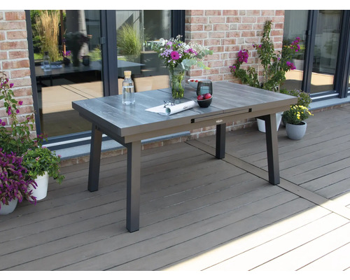 Table de jardin extensible sur une terrasse avec des fleurs et des décorations.