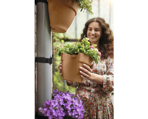 Frau hält Pflanztopf für die vertikale Gartenbewässerung in den Händen