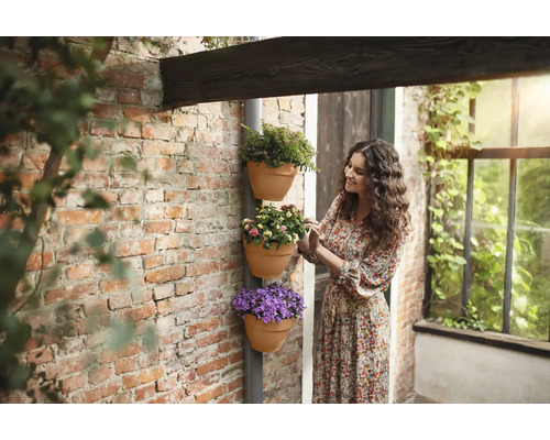 Frau betrachtet gestapelte Blumentöpfe an der Wand.