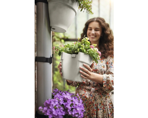 "Femme tenant un pot de fleurs gris avec des fleurs 