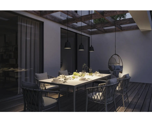 Terrasse avec table à manger, chaises et suspensions sous une pergola