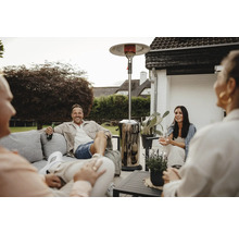 Personen sitzen im Garten mit einem Terrassenheizer für eine warme Atmosphäre.