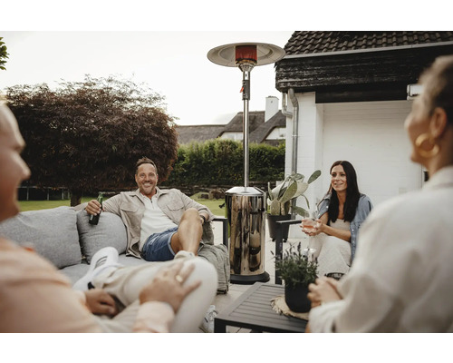 Personen sitzen im Garten mit einem Terrassenheizer für eine warme Atmosphäre.