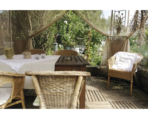 Dekorierter Gartentisch mit Rattan-Stühlen in heller, freundlicher Atmosphäre.