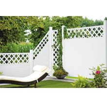 Vue de jardin avec clôture blanche, chaise longue et végétation verte