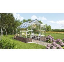 Serre avec étagères à plantes et coin salon dans le jardin.