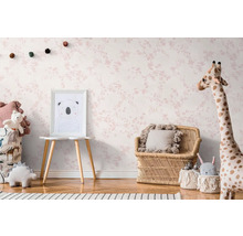 Kinderzimmer mit blütenmusterbedruckter Tapete, Rattanmöbeln und Stofftieren.