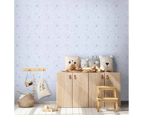 Kinderzimmer mit blau gemusterter Tapete, Holzschrank, Spielsachen und Dekorationen
