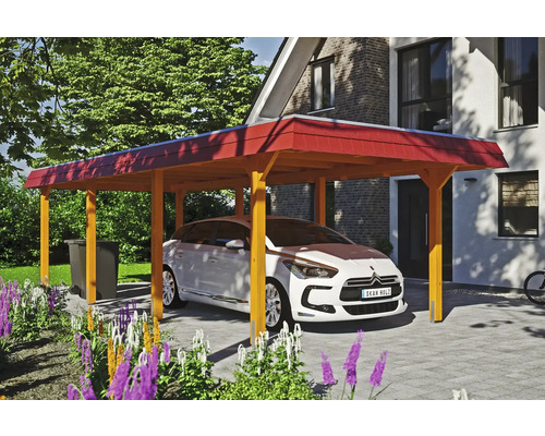 Ein Auto steht unter einem Holzcarport auf einem gepflasterten Hof vor einem Haus.