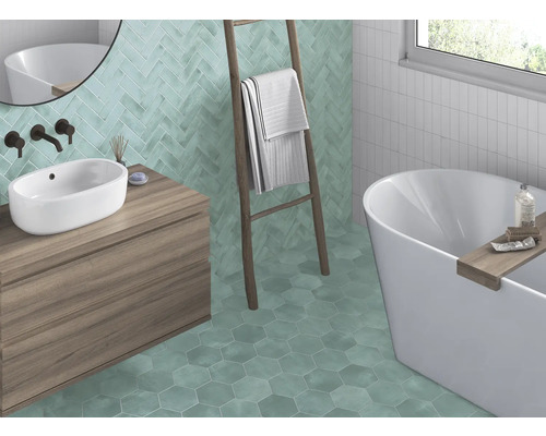 Badezimmer mit Waschbecken, Badewanne, Leiter und Wand- sowie Bodenfliesen in verschiedenen Formen