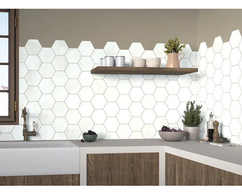 Scène de cuisine avec des carreaux hexagonaux blancs sur le mur, complétée par une étagère en bois et un plan de travail