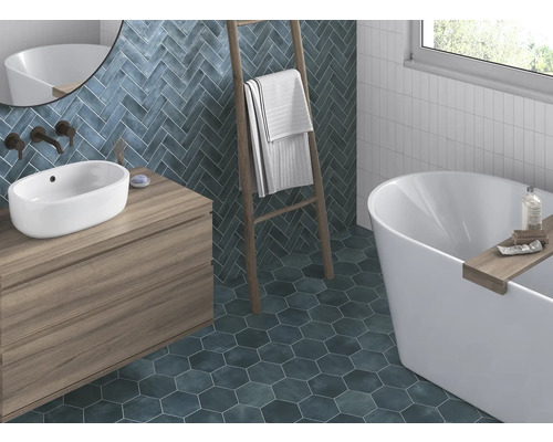 Badezimmer mit Waschtisch, Badewanne, Handtuchleiter und Wand- sowie Bodenfliesen