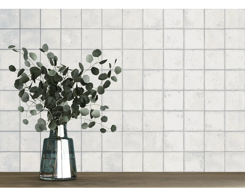 Wand mit quadratischen Fliesen und eine Vase mit Eukalyptus auf einem Holztisch