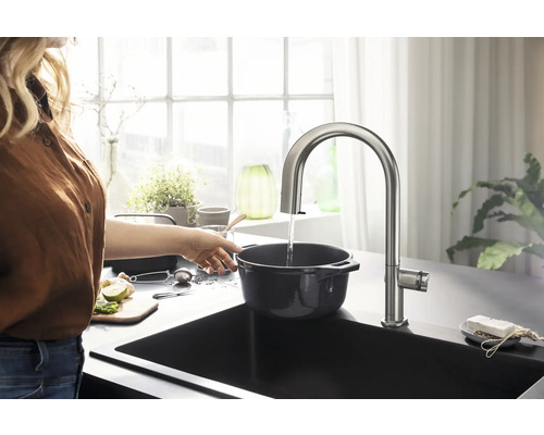 Edelstahl Küchenarmatur über einer Spüle mit einer Person, die Wasser in einen Topf füllt.