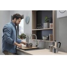 Heller Küchenraum mit Spüle, Wasserhahn und lächelndem Mann beim Kochen