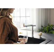 Femme remplissant d''eau une bouteille en verre sous un robinet dans une cuisine moderne.