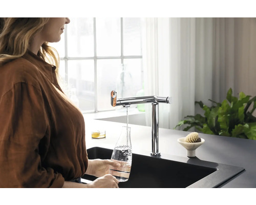 Femme remplissant d''eau une bouteille en verre sous un robinet dans une cuisine moderne.