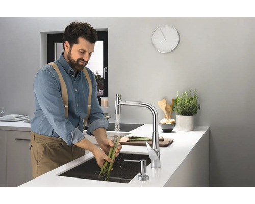 Un homme lave des asperges dans une cuisine moderne avec un robinet d''évier.