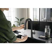 Eine Person füllt ein Glas Wasser mit einer schwarzen Küchenarmatur in einer modernen Küche.