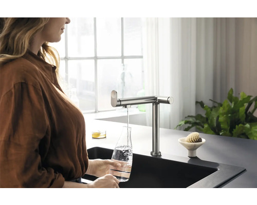 Femme remplissant une bouteille d''eau sous un robinet de cuisine
