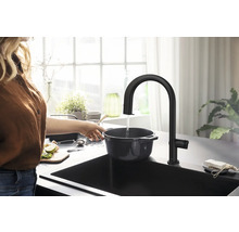 Femme remplit une casserole dans un évier avec un robinet