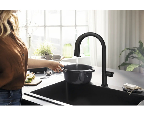 Frau befüllt Topf unter Küchenarmatur in Spüle