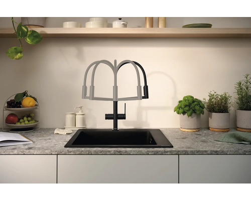 Évier de cuisine avec robinet et douchette extractible devant une crédence de cuisine avec des herbes aromatiques