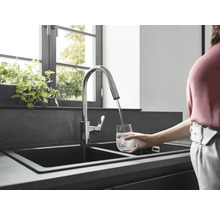 Spültischarmatur mit schwenkbarem Auslauf füllt ein Glas Wasser in einer modernen Küche.