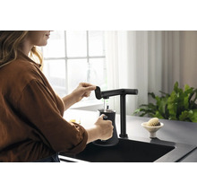 Femme remplissant une tasse avec un robinet de cuisine noir au-dessus d''un évier