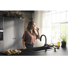 Femme buvant de l''eau dans une cuisine lumineuse avec évier et robinet