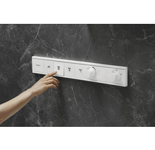Main actionnant le thermostat de douche sur un mur en marbre