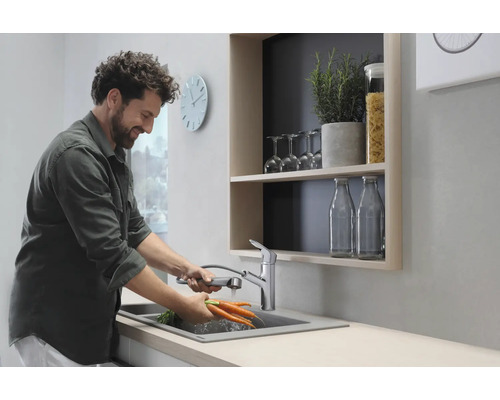 Un homme lave des carottes dans une cuisine moderne avec un robinet d''évier