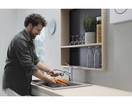 Homme lavant des carottes dans un évier de cuisine avec robinet extensible