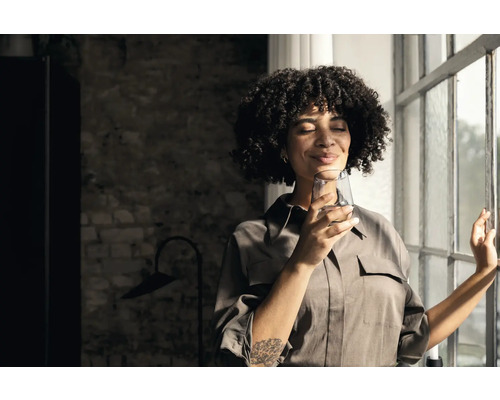 Frau hält Glas Wasser am Fenster