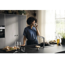 Femme buvant de l''eau à l''évier de la cuisine.