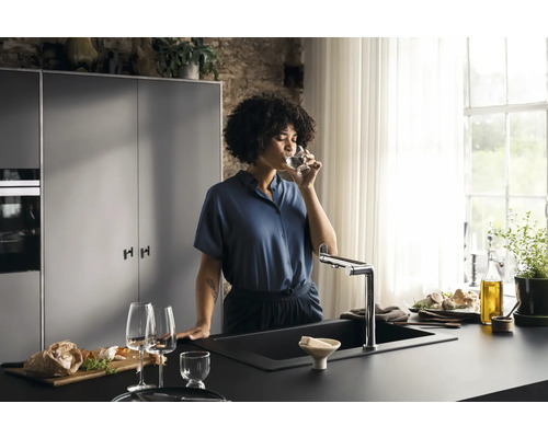 Cuisine moderne avec évier, robinet et une femme buvant un verre d''eau