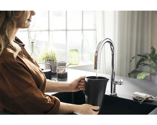 Frau füllt Wasser in einem Krug an einer Küchenarmatur