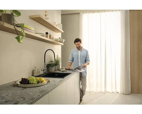 Cuisine lumineuse avec évier, robinet et un homme souriant lisant un livre