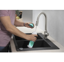 Eine Person befüllt eine Hansgrohe-Wasserflasche am Wasserhahn in einer Spüle.