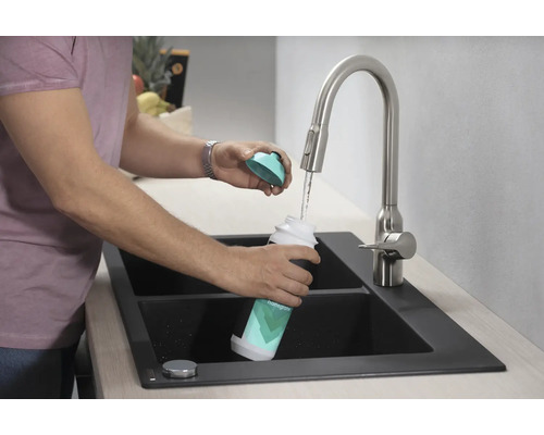 Eine Person befüllt eine Hansgrohe-Wasserflasche am Wasserhahn in einer Spüle.
