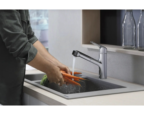 Une personne lave des carottes dans un évier avec un robinet.