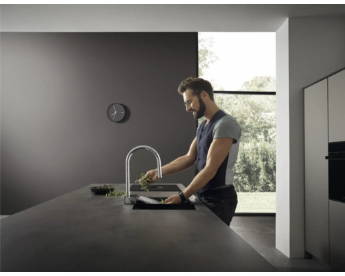 Mann wäscht Kräuter in einer modernen Küche mit Spültischarmatur