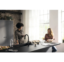 Cuisine lumineuse avec deux femmes à un comptoir de cuisine avec évier et robinet, vaisselle, ingrédients et ustensiles de cuisine.