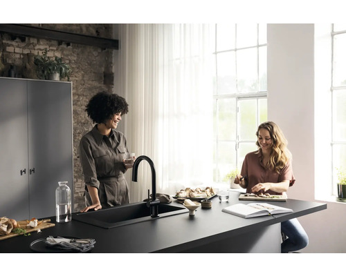 Helle Küche mit zwei Frauen an einer Arbeitsplatte mit Spüle und Armatur, während sie kochen und sich unterhalten