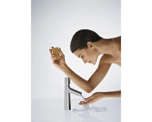 Frau wäscht ihre Hände mit Seife an einem verchromten Wasserhahn