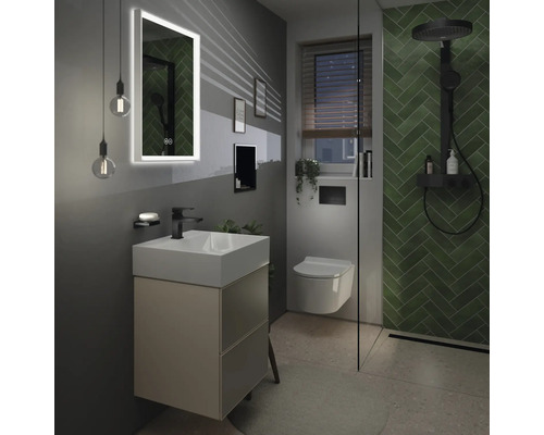 Salle de bains moderne avec lavabo, miroir éclairé, toilettes et douche avec carrelage vert