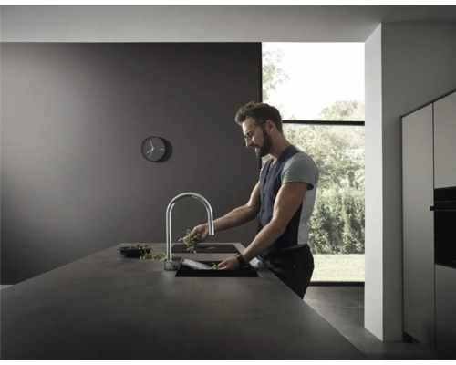 Moderne Küche mit Armatur, Spüle und einer Person, die Kräuter wäscht