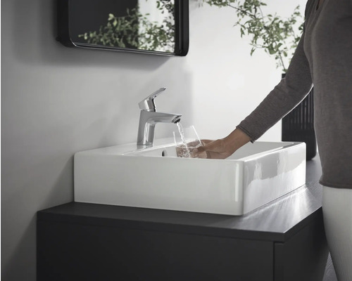 Salle de bains moderne avec lavabo rectangulaire, robinet et une personne remplissant un verre d''eau